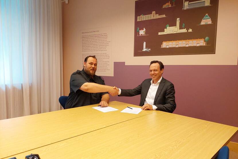 Victor Zuydweg en Ronald van den Hoogen beklinken partnerschap door elkaar de handen te schudden na ondertekening