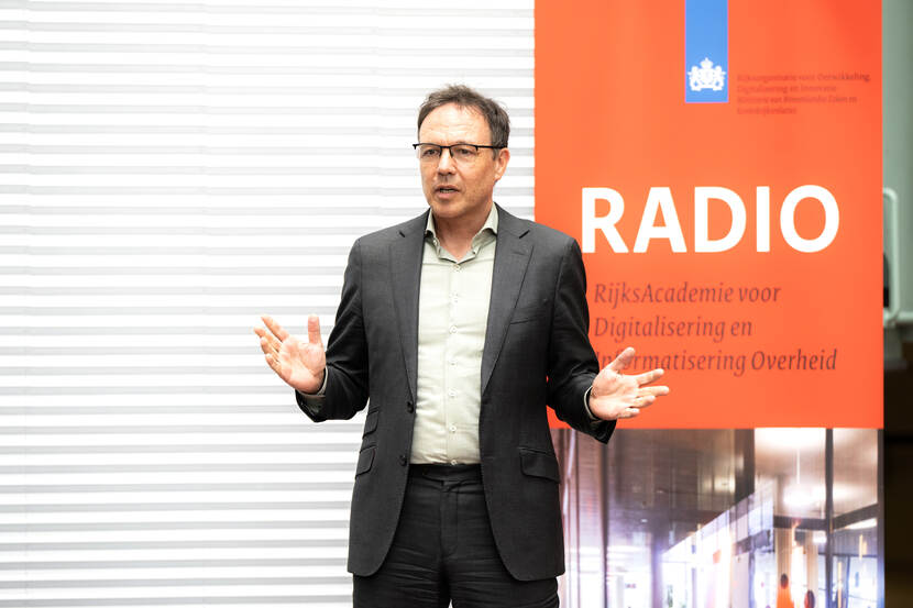 Ronald van den Hoogen tijdens officiële opening leerjaar op het podium tijdens toespraak naast RADIO banner