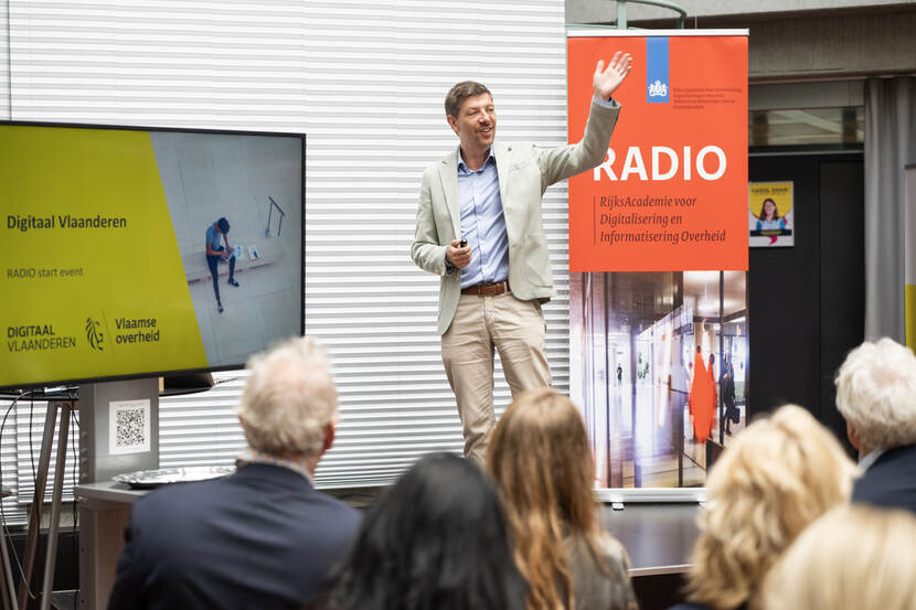 Tony Vanderstraete vertelt levendig op podium over Digitaal Vlaanderen naast banner RADIO