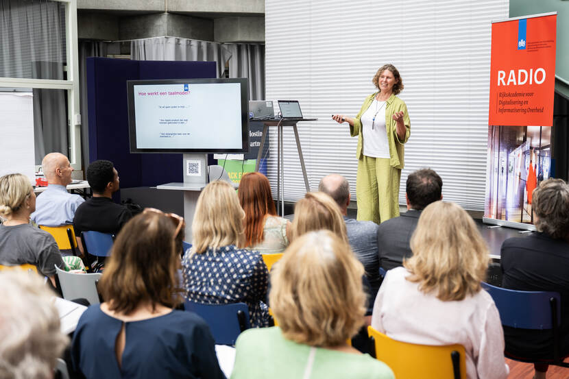 Presentatie op podium naast powerpoint door Joitske Hulsebosch