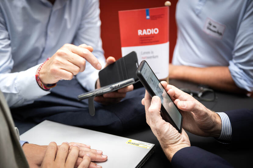 Telefoons in handen om LinkedIn profielen te delen met elkaar.